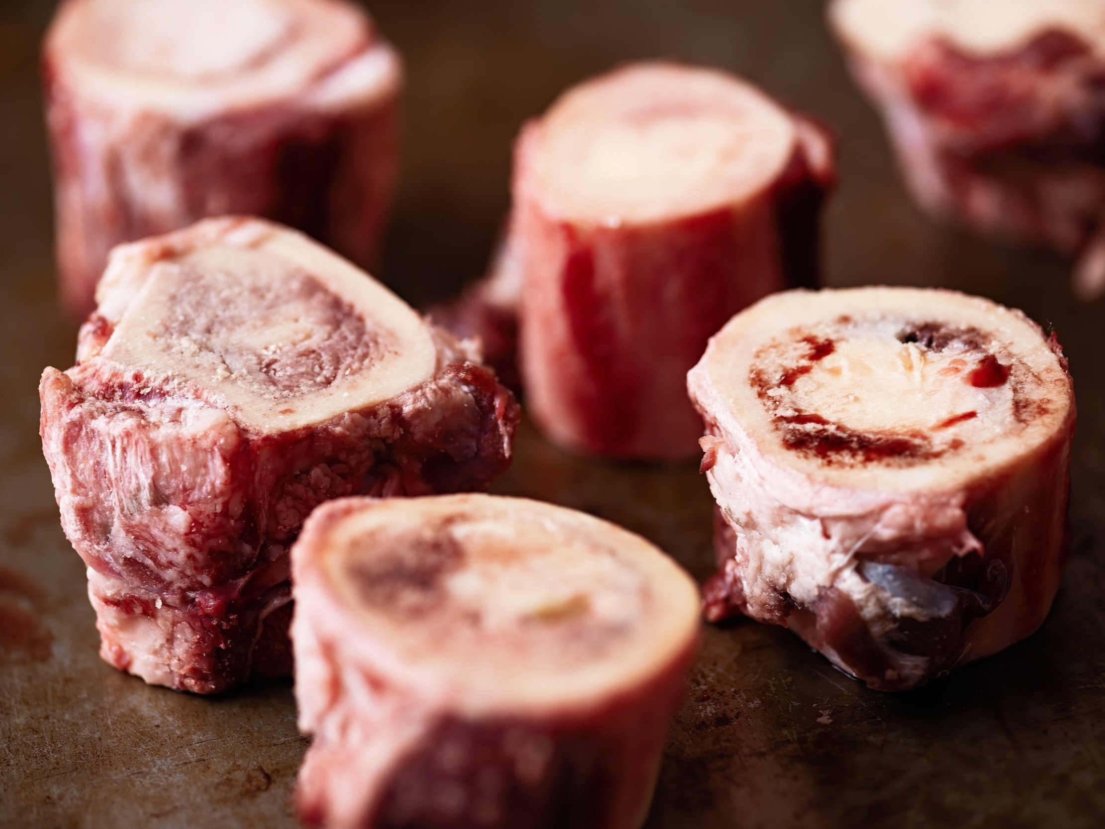 beef_bones_soup Close-up of several pieces of raw beef bone marrow, showcasing their rich, fatty interiors and smooth surfaces, ideal for culinary uses like broths and savory dishes.